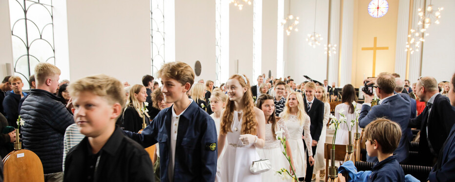 Em flok unge konfirmander på vej ned ad kirkegulvet efter deres konfirmation