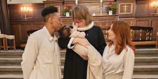 Pastor Maria holds a newly baptized child whose parents stand on either side