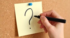 Et ai-genereret billede af en hånd, der skriver et spørgsmålstegn på en post-it