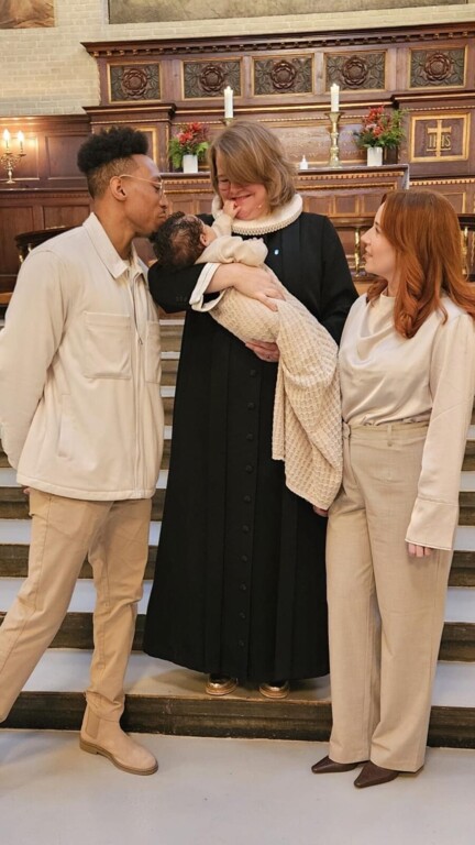 Pastor Maria holds a newly baptized child whose parents stand on either side