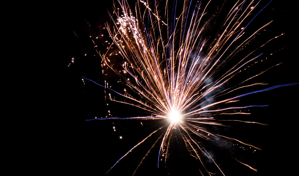 En nytårsraket eksploderer i blå og gyldne striber