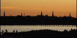I en sommersolnedgang ses Københavns kirketårne i sort silhouet