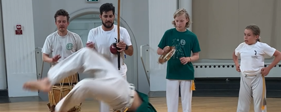 Fem unge mennesker danser capoeira