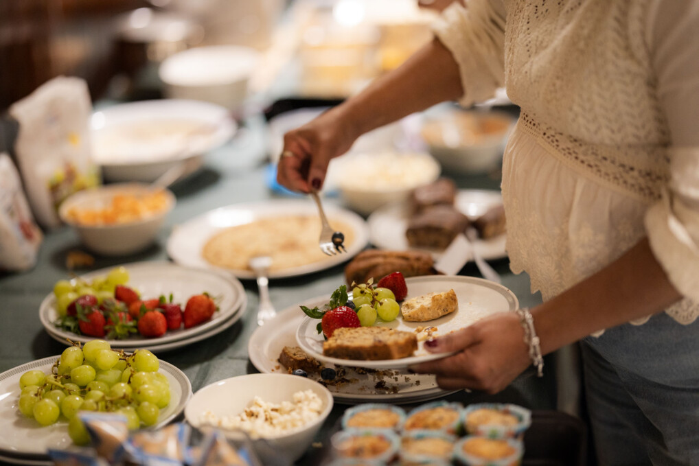A decked table with a green table cloth presents Danish meat balls, vegan butter, bread and many other delicious dishes