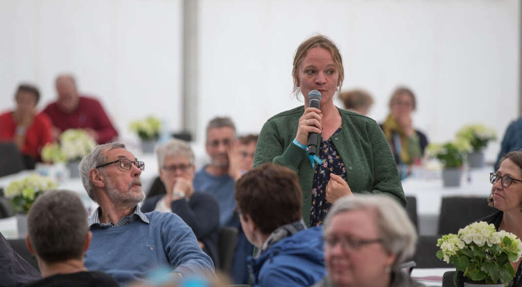 Kvinde med mikrofon taler til en forsamling