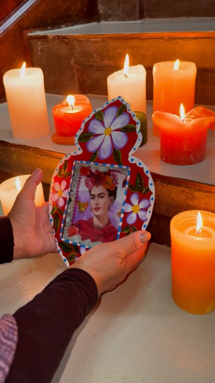 A woman holds a colour frame and a picture of Frida Kahlo