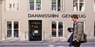 en mand går forbi en genbrugsbutik i gågaden