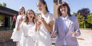 Four teenagers celebrate their confirmation on a sunny day outside a church