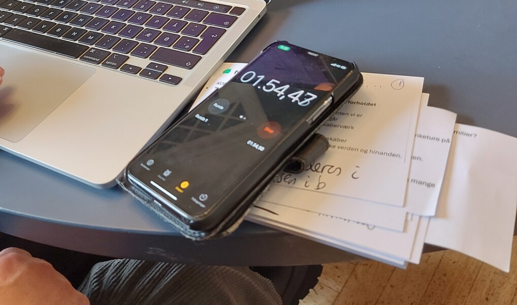 En mobiltelefon på et skrivebord tager tid i forbindelse med en skriveøvelse