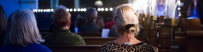 to unge mennesker sidder ved siden af hinanden på en kirkebænk