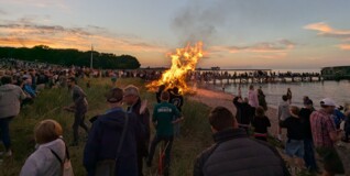 midsummer on the beach in copenhagen. a big bonfire in the middle, surrounded by silhouttes of people
