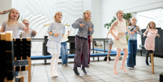 Børn på 8-9 år danser i Skelgårdskirkens hvide kirkerum