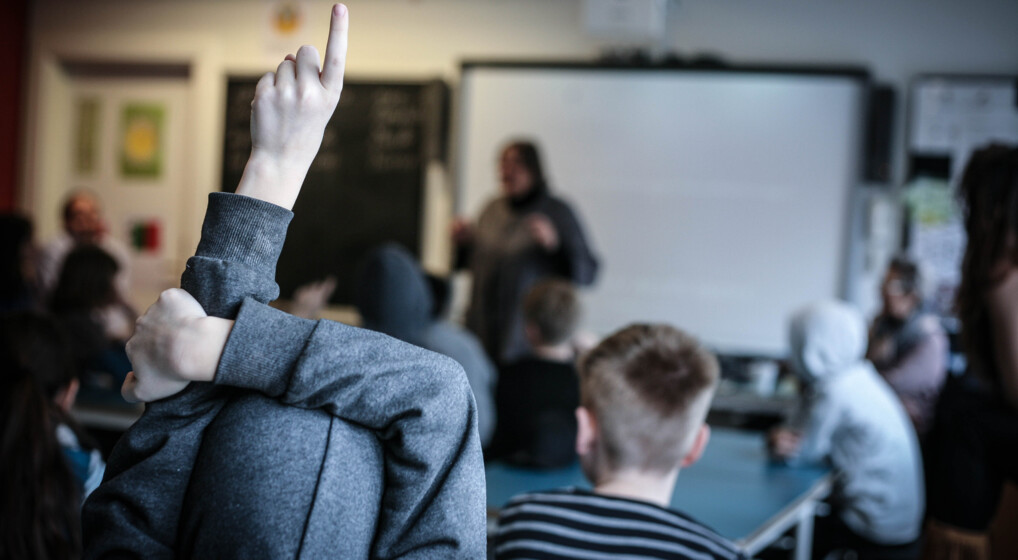 DinTro-MinTro En skoleelev rækker hånden op under et besøg fra din tro-min tro på en skole